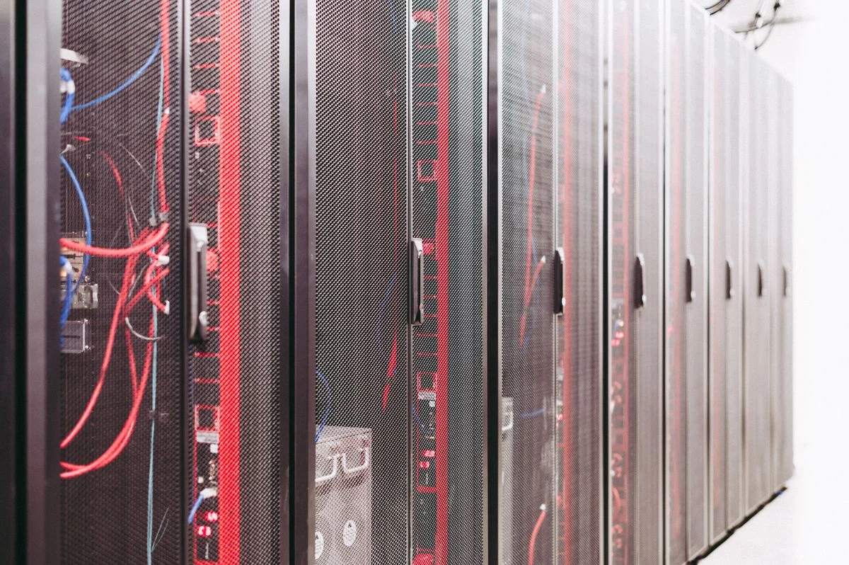 黒いメッシュ扉のサーバーラックが並ぶ通路。基幹業務へのAI実装を担う話題のイメージ
