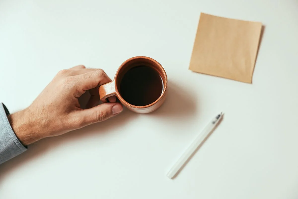 コーヒーカップを持つ手元とメモ用紙。「まとめ」の話題のイメージ