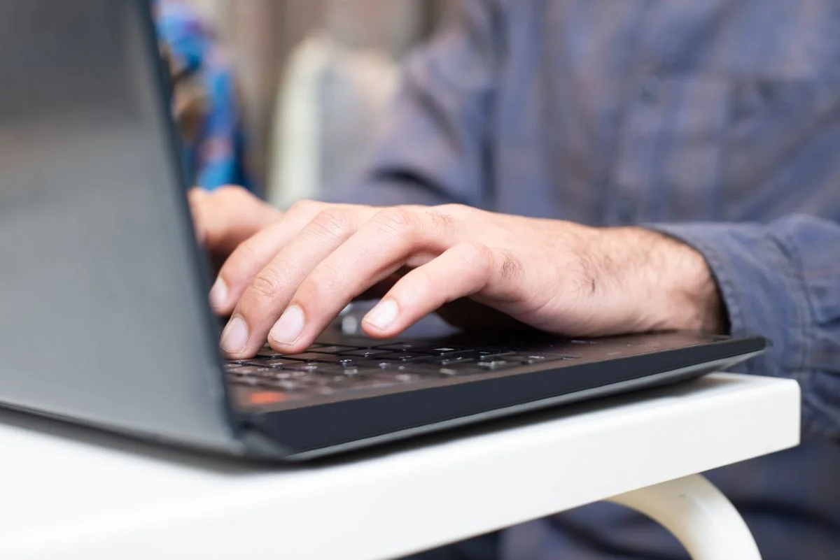 ノートPCのキーボードを打つ手元。「AIに個人情報を入れると何が起きるか」の話題のイメージ