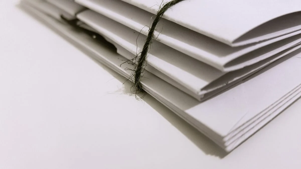 紐で束ねた白い書類の山。3社の提案書を並べて前提条件を比べる話題のイメージ